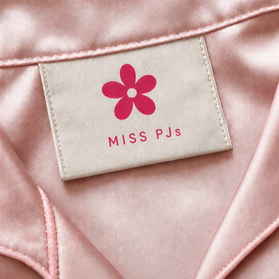 The woven Miss PJs label sewn onto blush satin